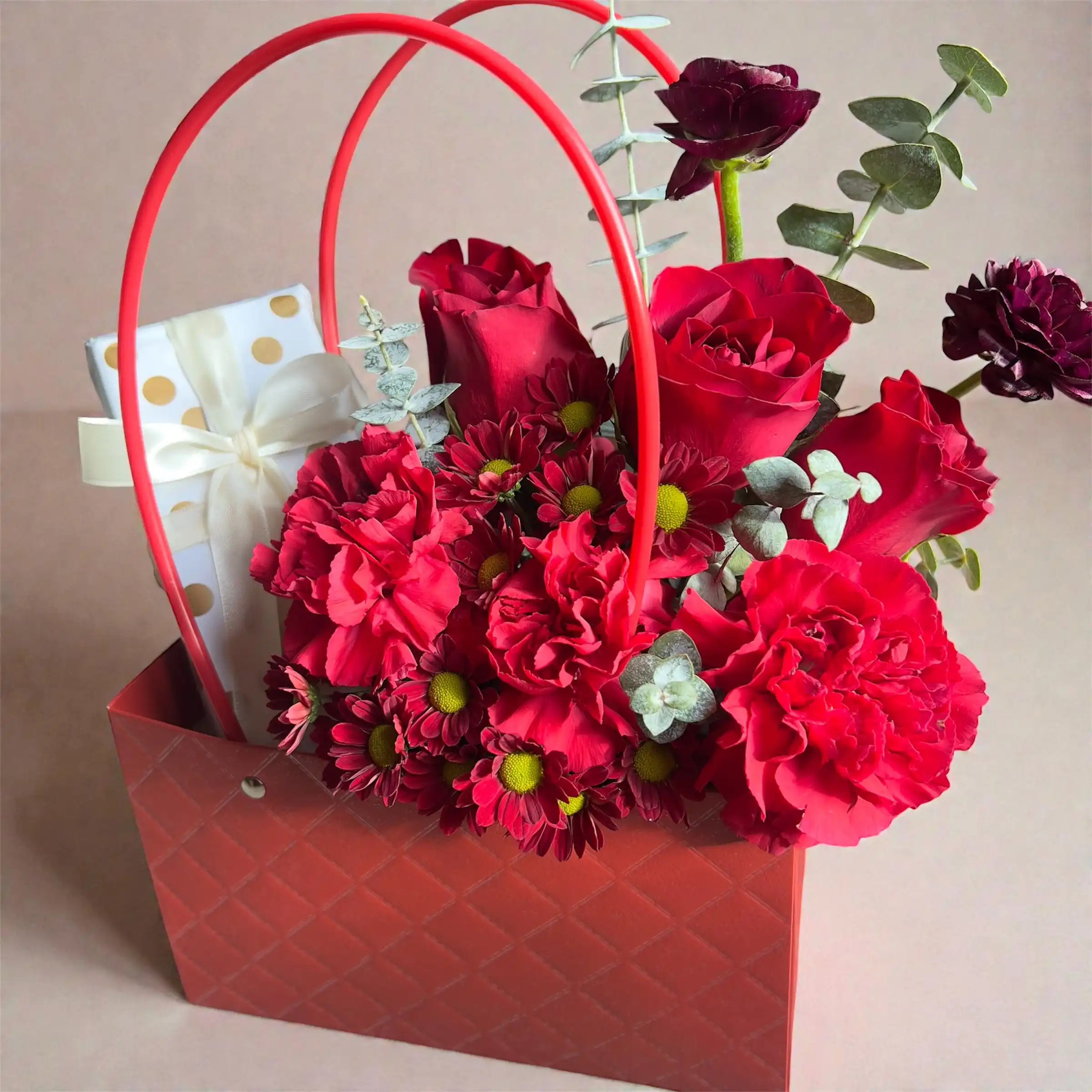Crimson red rose bloom box with red carnations, burgundy flowers, eucalyptus greenery, and gift box