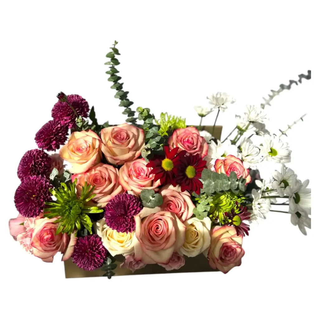 Peach and blush roses with burgundy chrysanthemums in a gold rectangular flower box on white background
