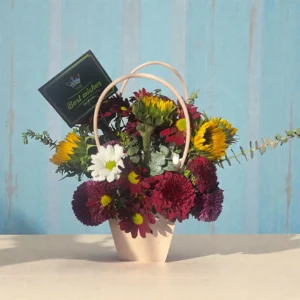 Sunflower and mixed floral basket with burgundy blooms, white daisies, eucalyptus greenery, and best wishes card